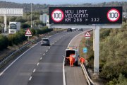 Operaris de l'SCT recollint una caixa radar al tram ebrenc de l'AP-7, sota una panell que informa de la nova limitació de velocitat.