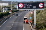 Operaris de l'SCT recollint una caixa radar al tram ebrenc de l'AP-7, sota una panell que informa de la nova limitació de velocitat.