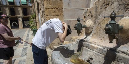 Un jove es refresca en una de les fonts de les escales de la catedral de Tarragona buscant alleujar les altes temperatures.