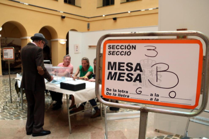 Un cartell indicatiu i d'un elector votant en un dels col·legis electorals de la ciutat de Tarragona.