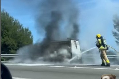 Un bombero apagando el fuego que quemaba uno de los vehículos