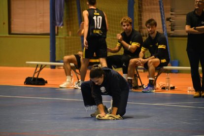 Una membre del CB Cambrils eixugant aigua de la pista durant un partit.