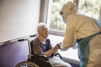Una anciana amb una infermera amb l'EPI durant la pandèmia covid-19.