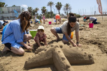 Una família participant en el taller d’estructures de sorra a la platja de Ponent de Salou