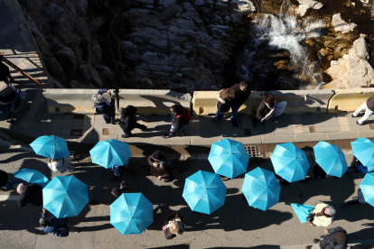Prop d'un miler de persones tenyeixen de blau la llera del riu amb paraigües per simbolitzar una onada