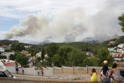 Diversos veïns de la Pobla de Montornès contemplen la columna de fum de l'incendi. Imatge del 5 d'agost de 2016