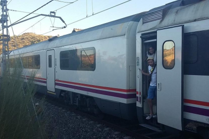 Usuaris d'un tren aturat entre Flix i Móra per una avaria d'electrificació a la línia esperen que els vinguin a rescatar per poder continuar el viatge el 18 de juliol del 2016. Pla general