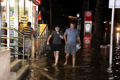 Plano general de dos personas andando descalzas por la acumulación de agua a la zona de la plaza Europa de Salou, la noche del 31 de agosto del 2017