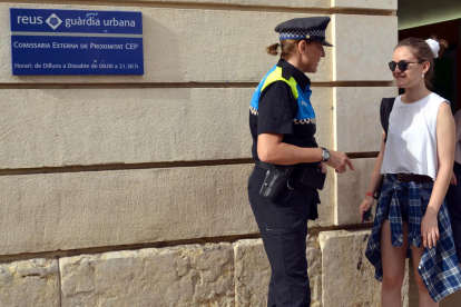 Una agent de la Guàrdia Urbana de Reus atén una ciutadana a les portes d'una de les CEP de la ciutat. Imatge de l'1 d'agost de 2017 (horitzontal)