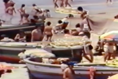 Una imatge del vídeo, on es poden veure persones a la platja amb les barques sobre l'arena.