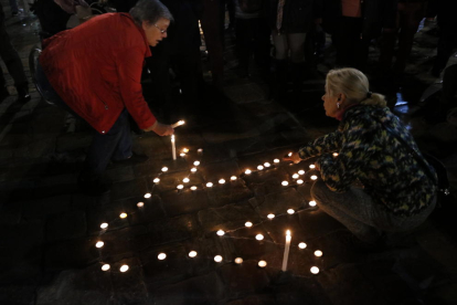 Plano cerrado de dos personas encendiendo velas para formar una silueta humana en la plaza del Mercadal.