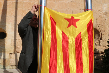 El portavoz de Alternativa Baix Gaià, Lluís Suñé, cuelga una estelada entre dos palos del Ayuntamiento de Torredembarra.