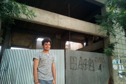 Abdulnahab Afridi, de 17 años, sonríe en la entrada del edificio, donde vive desde hace unos meses.