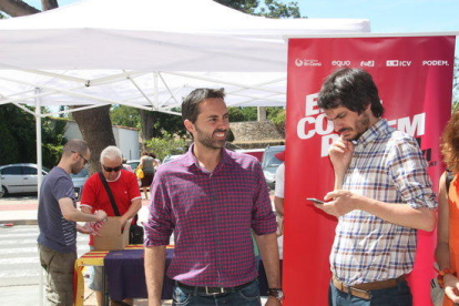 L'eurodiputat Ernest Urtasun, mirant el seu telèfon mòbil, amb el candidat número 2 pel Senat d'En Comú Podem per Tarragona, el tortosí Jordi Jordan, amb la carpa de la coalició al fons.