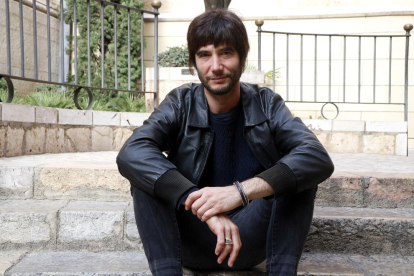 El músic i compositor, Joan Masdéu, assegut en unes escales del carrer de les Peixateries de Reus.