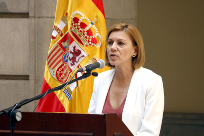 La ministra de Defensa, María Dolores de Cospedal, hablando con una bandera española detrás.