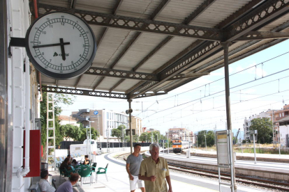 El rellotge de l'estació de Tortosa mentre arriba un dels trens des de Barcelona amb retard.