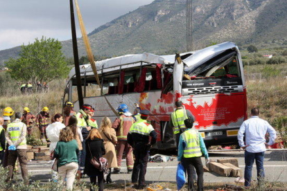 Efectius dels Bombers i Mossos observant l'autobús accidentat un cop la grua l'ha aixecat