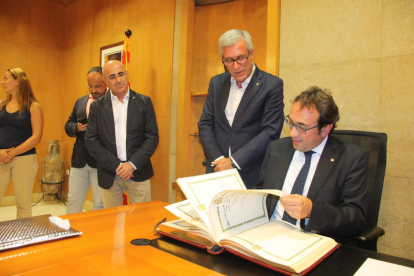 El conseller de Territorio y Sostenibilidad, Josep Rull, hojeando el Libro de Honor del Ayuntamiento de Tarragona, bajo la mirada del alcalde, Josep Fèlix Ballesteros.
