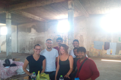 La Lina, el Gio i la Janina, a l'esquerra, somriuen junt amb un grup de refugiats a l'interior d'un edifici abandonat.