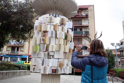 Una mujer fotografiando un panel publicitario forrado con libros en la Rambla Catalunya de Vila-seca