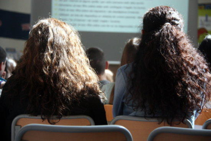 Dues estudiants, d'esquena, en una aula d'una escola.