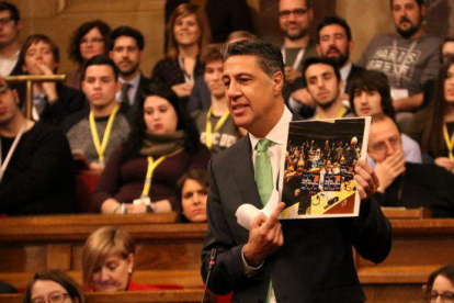 El líder del PPC, Xavier García Albiol, con una fotografía de algunos asistentes a la conferencia del Parlamento Europeo, durante la sesión de control al presidente, el 25 de enero de 2017.