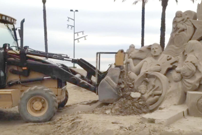 Imagen de la máquina excavadora derribando el pesebre de arena.