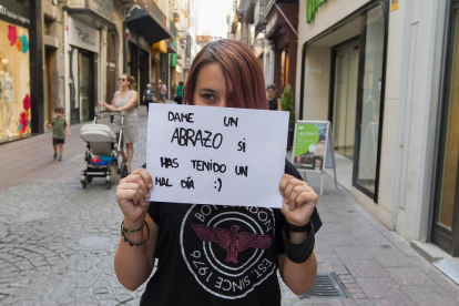 Imatge de l'Olga Mateo amb el cartell en qüestió tapant-li el rostre al carrer Monterols.