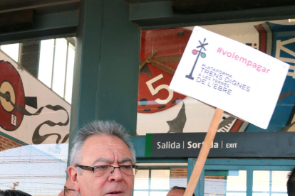 Pla americà del representant de la plataforma Trens Dignes, Josep Casadó, mostrant el seu bitllet d'Euromed per al viatge reivindicatiu amb una pancarta amb el lema 