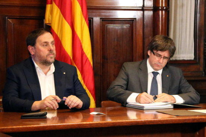 El vicepresident Oriol Junqueras observa el president de la Generalitat, Carles Puigdemont, signant, el 6 de setembre de 2017