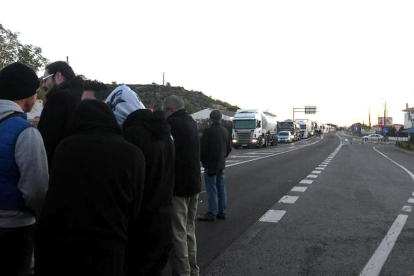 Veïns agrupats en primer pla, tallant la carretera N-340, davant de la cua de vehicles retinguts, a les Cases d'Alcanar. Imatge del 6 de novembre de 2017 (horitzontal)