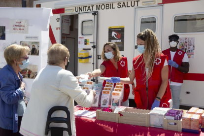Imatge de dues volutàries de la Creu Roja atenent a dues dones d'edat avançada.