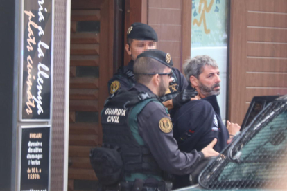 Dos agentes de la Guardia Civil se llevan a un detenido en Sabadell en el marco de la operación que ha acabado con nueve miembros de CDR arrestados.
