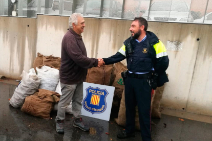 Pla conjunt d'un agent dels Mossos i el pagès propietari de les garrofes robades a la Canonja en el moment que es va efectuar el retorn del fruit. Imatge del 21 d'octubre de 2019