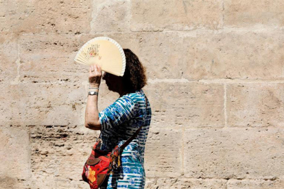 Imagen de una mujer protegiéndose del sol con un abanico.