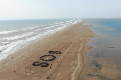 El assistens a l'acte del MOLDE han configurat les lletres SOS a la platja del trabucador.