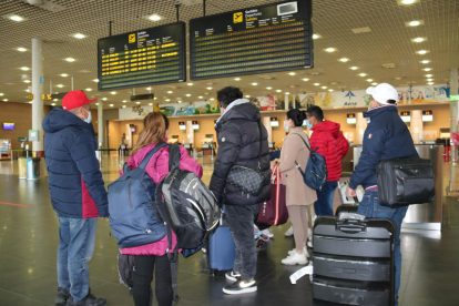 Un grupo de pasajeros miran el tablero de salidas del aeropuerto de Reus.