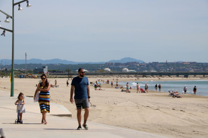Plano abierto de una familia caminando por el paseo marítimo de la Pineda, a Vila-seca.