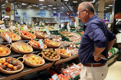 Un home compara els preus de la verdura en un supermercat de Barcelona.