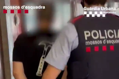 Un agente de Mossos llevado-se uno de los detenidos.