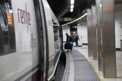 Una persona entrando en un tren AVE en la estación de Sants de Barcelona.