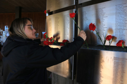 Una dona col·loca clavells al Memorial de les Camposines.