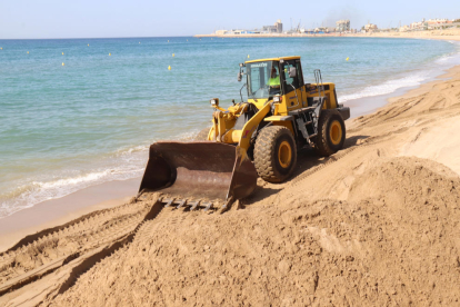 Una máquina mueve arena en la playa del Miracle de Tarragona.