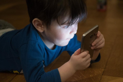 Un nen petit fixat amb una pantalla de mòbil.