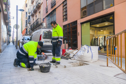 Dos operarios, ayer durante los trabajos destinados a la instalación del pilón, en la calle Armanyà.