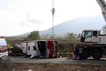 Una grua aixecant l'autocar accidentat a l'AP-7 a Freginals