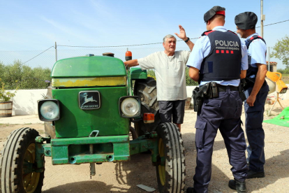 Pla general de dos agents dels Mossos d'Esquadra conversant amb un pagès al costat del seu tractor en un mas de Vallmoll (Alt Camp), el 7 de juliol del 2017