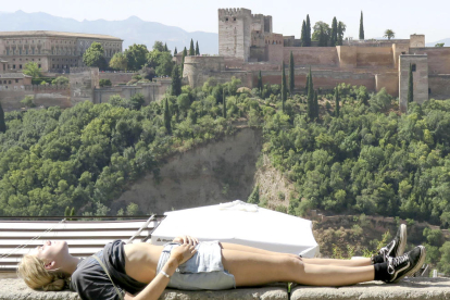 Una turista toman el sol en la ciudad de Granada.