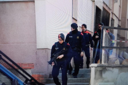Imagen de agentes de los Mossos D'Esquadra saliendo de realizar un registro en un piso en el barrio de Sant Salvador.